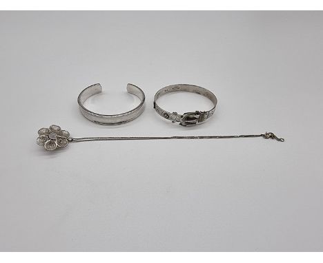 A silver bangle, having belt buckle clasp and chased decoration, by E J Ltd, Birmingham 1976; together with a modern white me