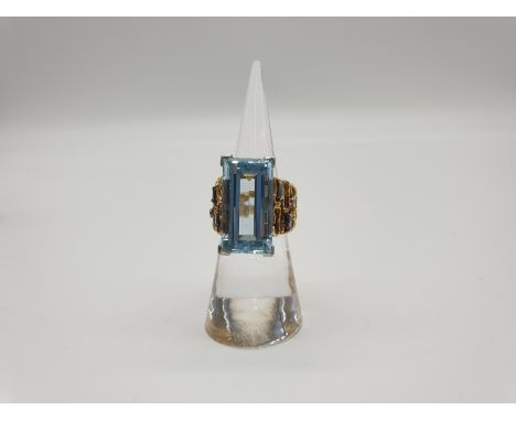 (NB) A 1970s large aquamarine ring, estimated at 14ct and six small diamonds to the bark effect pierced shank, size K. 