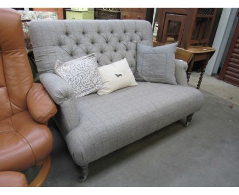 A tweed design grey upholstered two seater sofa with button back, turned legs to castors, scratch hole to seat 