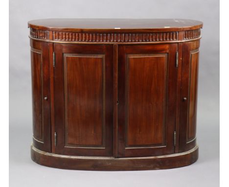 A 19th century-style mahogany bow-front dwarf cabinet with a moulded frieze, fitted shelf enclosed by two pairs of fielded pa