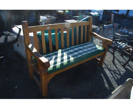 A large heavy Oak garden Bench with cushion and waterproof cover.