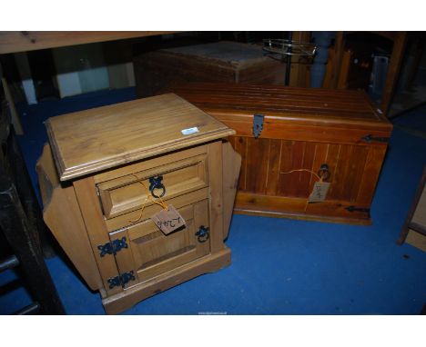 A stained wood  trunk with ironwork detail and a lighter rustic bedside cupboard with drawer