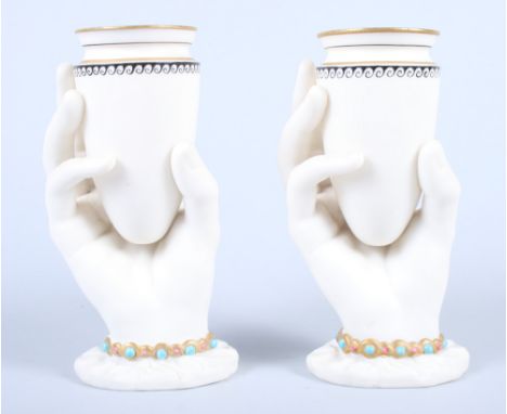 A pair of late Victorian Royal Worcester Parian ware spill holders, in the form of a cuffed jewelled hand holding an amphora 