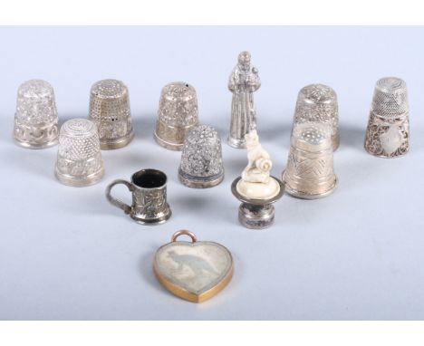 Seven silver thimbles, a white metal filigree thimble, a 9ct gold and carved hardstone heart-shaped locket with kangaroo deco