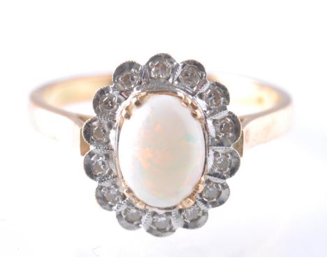 A 14ct gold opal and diamond ring. The ring being set with a central opal cabochon surrounded by a halo of diamonds. Assay ma