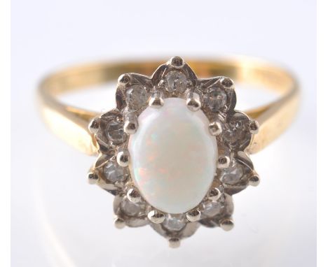 A hallmarked 18ct gold opal and diamond culster ring. The ring having a central oval opal cabochon surrounded by a halo of di