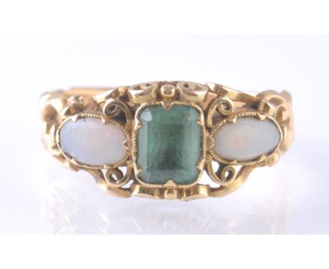 A Victorian 18ct gold emerald and opal ring. The central emerald cut emerald measuring 7mm by 5mm flanked by 2 cabochon opals