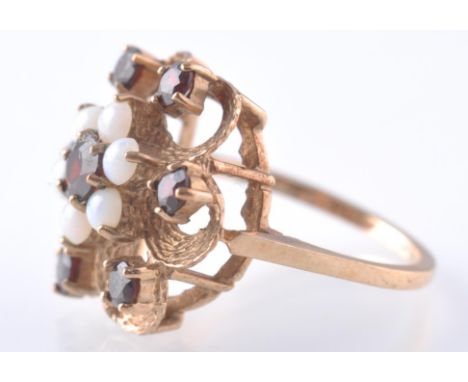 A hallmarked 9ct gold garnet and opal dress ring. The ring being set with a central garnet surrounded by a halo of opal with 