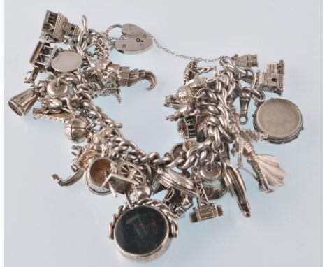 A hallmarked 925 silver curb link charm bracelet strung with 35 plus charms including seahorse church, bell, matador, oil lam