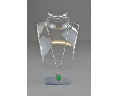 A Chinese green stone possibly jade cabochon mounted on a silver-coloured chain in a necklace. Stone 7mm x 18mm 