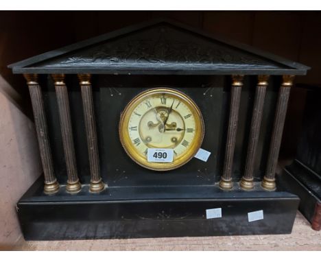 A large late Victorian black slate cased mantel clock of architectural design with six flanking brass columns, visible escape