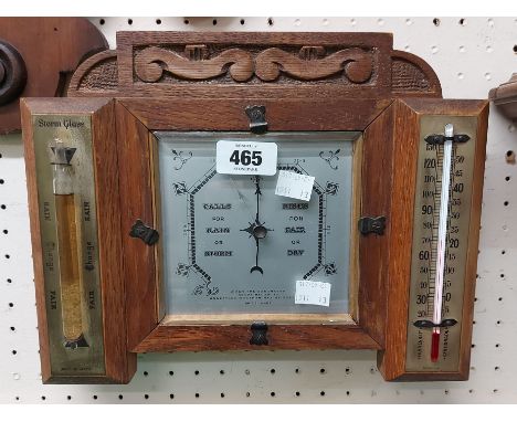 An early 20th Century carved oak framed wall barometer/thermometer with central aneroid works and flanking thermometer and 'S