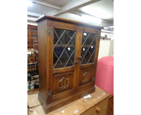 A 72cm vintage Webber Furniture oak cabinet with shelf enclosed by a pair of part leaded glazed panel doors, set on plinth ba