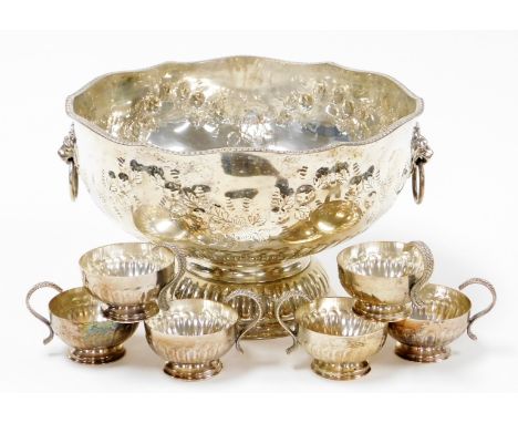 A silver plated punch bowl and cups, plated on copper, in late 19thC style, with lion mask handles and floral embossing, 20cm