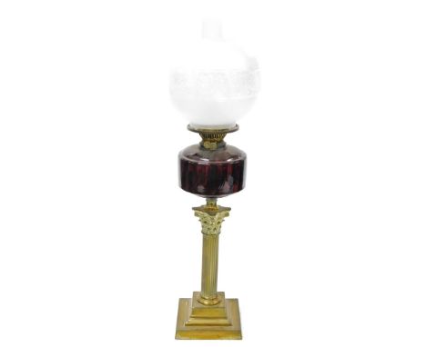 A late 19thC brass oil lamp, with a shade and reservoir, on a cranberry glass dome, on brass Corinthian column stepped base, 