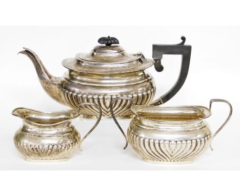 A George V silver three piece tea service, comprising teapot, milk jug, sugar bowl, the teapot with ebonised handle and knop,