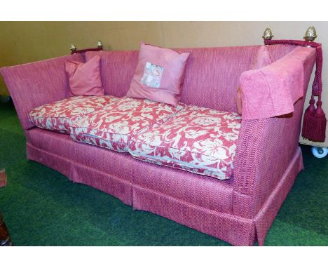 A Knole style three seater sofa, in a red upholstery, with brass acorn finials and ties, 80cm high, 225cm wide, 83cm deep.