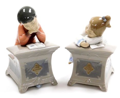 Two Nao porcelain figures, of children at desk, reading and writing, boy and girl, no.1403 and 1494, 16cm high (2).