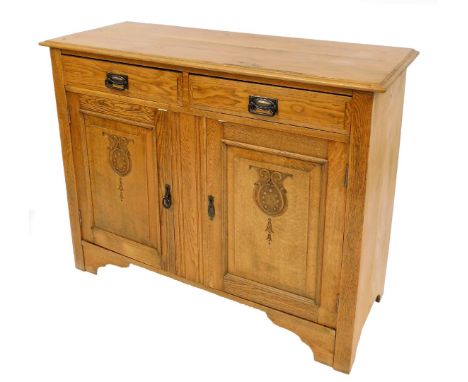 An Arts &amp; Crafts style light oak sideboard, with plain top above two short drawers and two cupboard doors with florally d