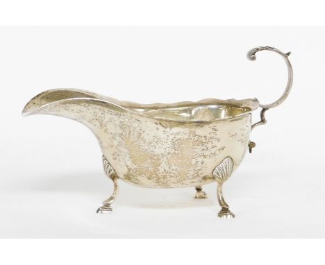 An Elizabeth II silver sauce boat, with fluted border, on rococo scroll handles, on tripod shell feet, Birmingham 1977, 4½oz.
