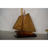 A wooden model of a yacht on black oval plinth