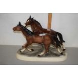 A large ceramic sculpture of two horses on oval frame