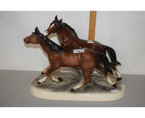 A large ceramic sculpture of two horses on oval frame