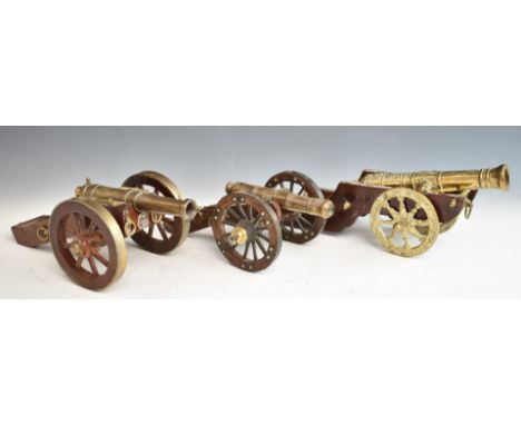 Three model cannon with brass or bronze barrels and wooden carriages, one with Royal Artillery or similar coat of arms to fro