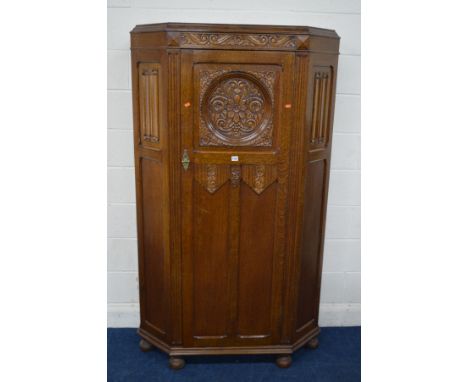 AN EARLY TO MID 20TH CENTURY OAK LINENFOLD HALL ROBE, with canted corners, carved floral detail to door enclosing a shelf and