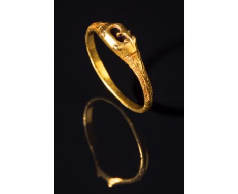 A MEDIEVAL GOLD FINGER RING, the R-shaped bezel encasing a sliver of garnet, the shoulders decorated with engraved leaves on 