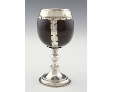 AN ENGLISH SILVER MOUNTED COCONUT CUP, EARLY 18TH C  the smooth coconut shell of fine patina in three notched and hinged stru