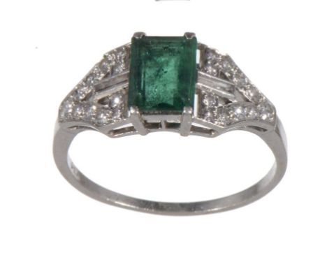 AN EMERALD AND DIAMOND RING  the step cut emerald between bifurcated shoulders set with baguette and round brilliant cut diam