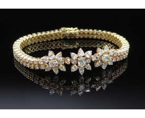 having three central flower heads flanked by two rows of round cut diamonds totalling 3.9cts approx., 18cms long, 28.0gms in 