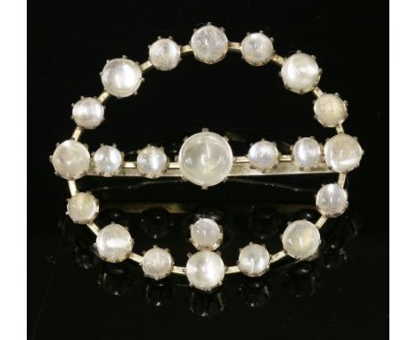 A silver moonstone buckle or belt or sash decoration, of oval form, claw set with graduated circular cabochon moonstones