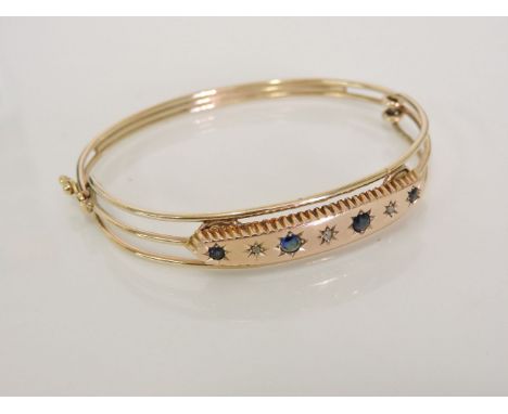 A gold three row bangle, with diamond and sapphire doublets centrepiece, later mounted from another bangle, 15.13g