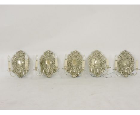 A set of four silvered two light wall lights, the cast backs with cherubs amongst garlands of fruit and flowers, each approxi