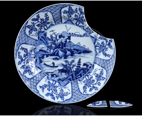 Porcelain dish with a blue and white decoration of a fisherman in a landscape surrounded by cartouches in which a floral deco