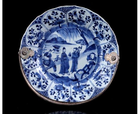 Porcelain dish with a blue and white decor of long lines and a servant with a horse in the center surrounded by flowers divid