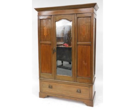 An Edwardian mahogany and inlaid double wardrobe, the outswept pediment over a single door, inset bevelled glass, enclosing a