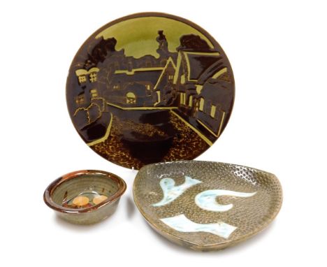 A Poole pottery charger, decorated with a village scene, with browns and yellows, printed marks, 35cm diameter, together with