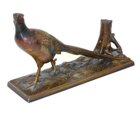 An early 20thC cold painted strike lighter, modelled with a pheasant before a tree stump, raised on a naturalistic rectangula