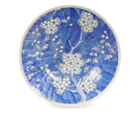 A Japanese blue and white porcelain charger, decorated with prunus blossom against a scale ground, restored, 18cm diameter.