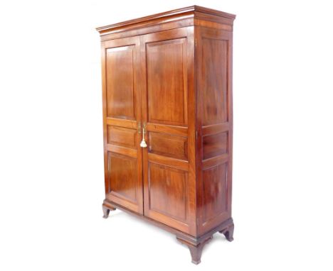 An early 20thC French cherry wood armoire, the pediment over a pair of panelled doors, opening to reveal a brass hanging rail