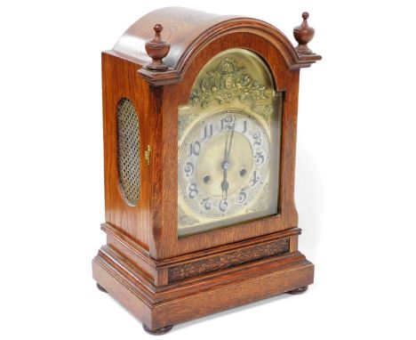 A late Victorian oak cased mantel clock, the brass break arch dial with a mask and floral spandrels, silvered chapter ring be