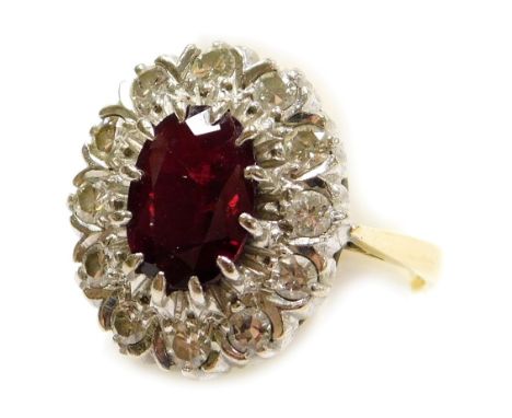 A ruby and diamond ring, the oval cut ruby and surround of diamonds, set in a white and yellow metal mount, stamped 18ct, rub