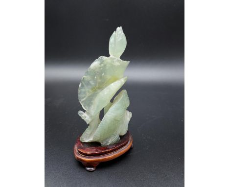 A Chinese hand carved jade sculpture depicting a koi carp and flower.Sat on a wooden base [12.5cm in height] 