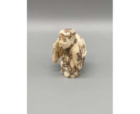 An Early 20th century Japanese hand carved bone netsuke of gentleman carrying a sack on his back. Signed. [4.7cm in height] 