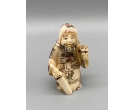 An early 20th century Japanese hand carved bone netsuke of a cloaked gentleman holding a sword and lantern. Signed. [5.5cm in