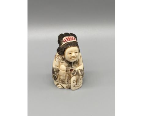 A Japanese hand carved bone netsuke of a women in an ornate robe. Signed. [5cm in height] 