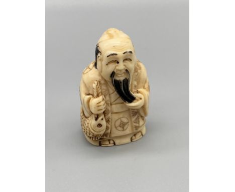 An early 20th century hand carved bone Japanese netsuke of an elderly gentleman stroking his beard and holding a fish. Signed